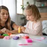 Une petite fille fait de la pâte à modeler sous l'oeil de sa maman